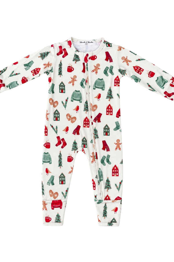A baby long-sleeve footed one-piece sleeper with a festive Christmas print on an off-white background. The print features red and green stockings, gingerbread men, Christmas trees, snowman figures, and small houses.