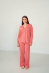 A woman modeling a matching two-piece pajama set with a red and white wavy geometric pattern, standing against a plain white studio background.