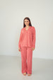 A woman modeling a matching two-piece pajama set with a red and white wavy geometric pattern, standing against a plain white studio background.