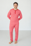 A man wearing a red abstract patterned long-sleeve pajama top and matching pants, standing barefoot against a plain light gray studio background.