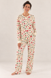 A woman modeling a matching long-sleeve pajama set with a holiday/winter pattern, standing against a plain white studio background.